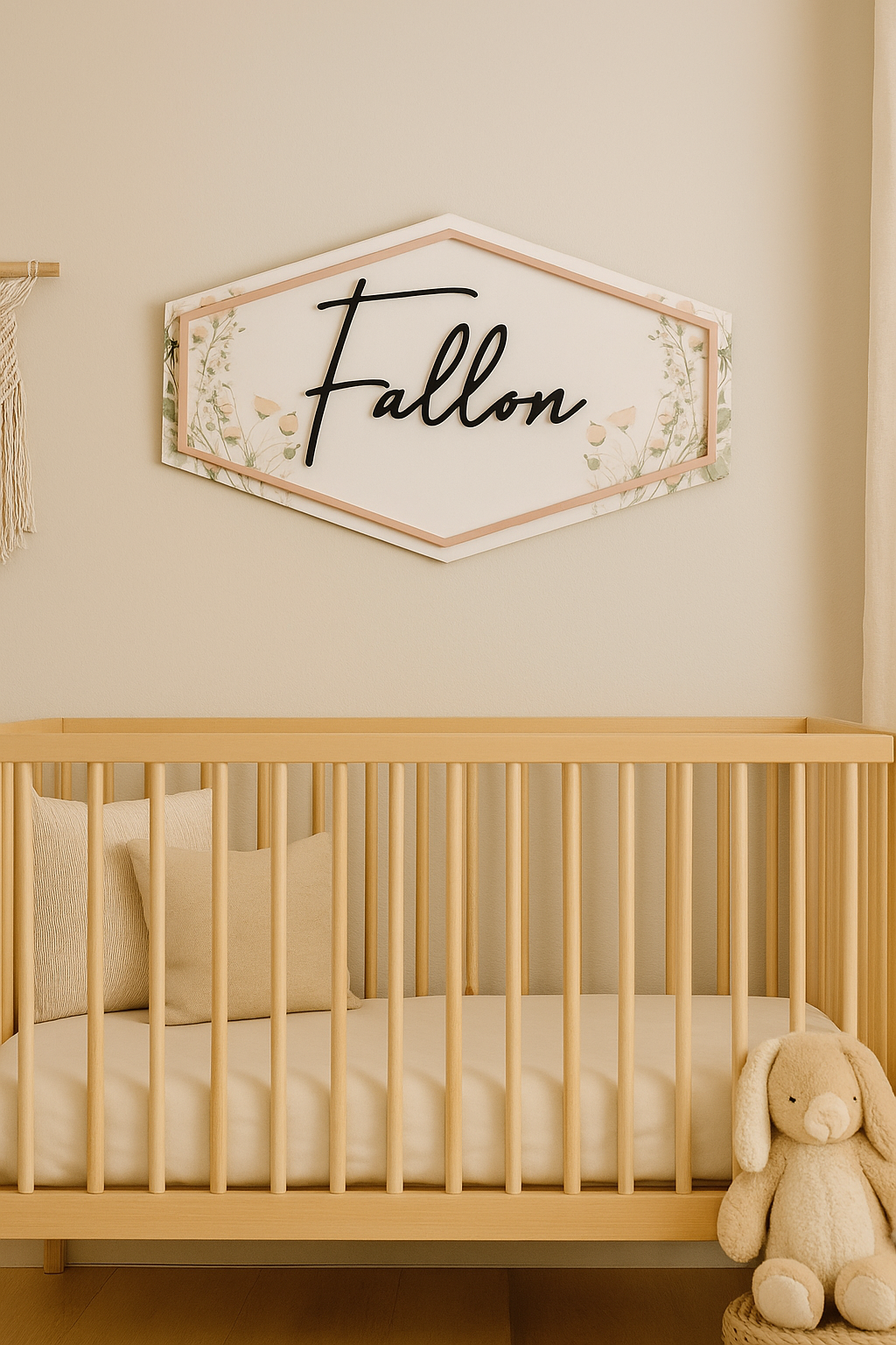 Custom floral name sign reading "Fallon" above a neutral crib, featuring raised script lettering and soft wildflower background.