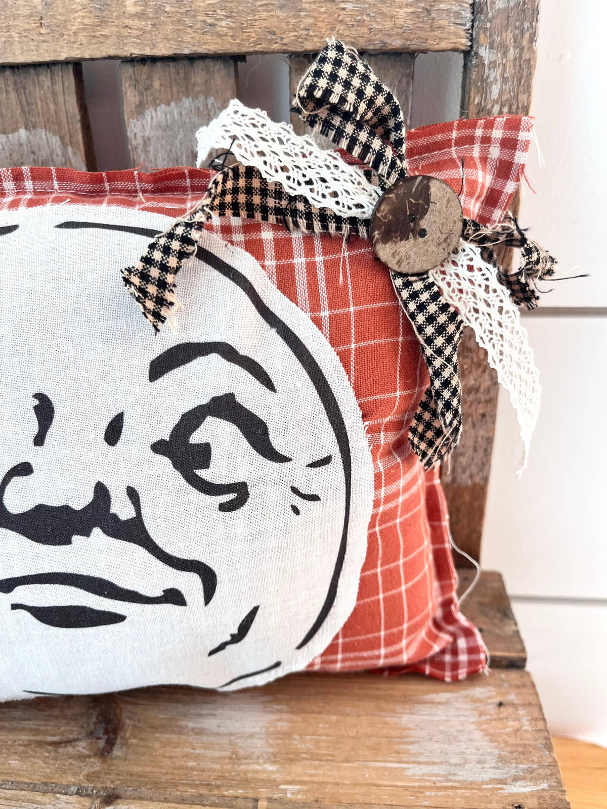Red plaid moon pillow with bow and decorative accent.