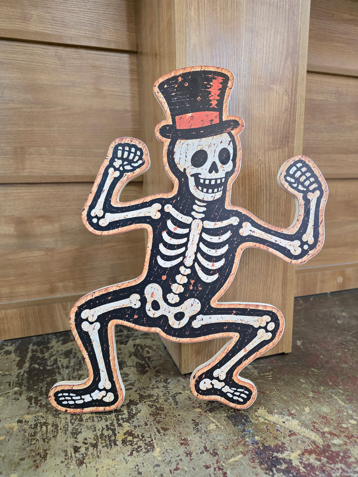 Vintage dancing skeleton Halloween sign with top hat, printed on wood in distressed black, cream and orange.