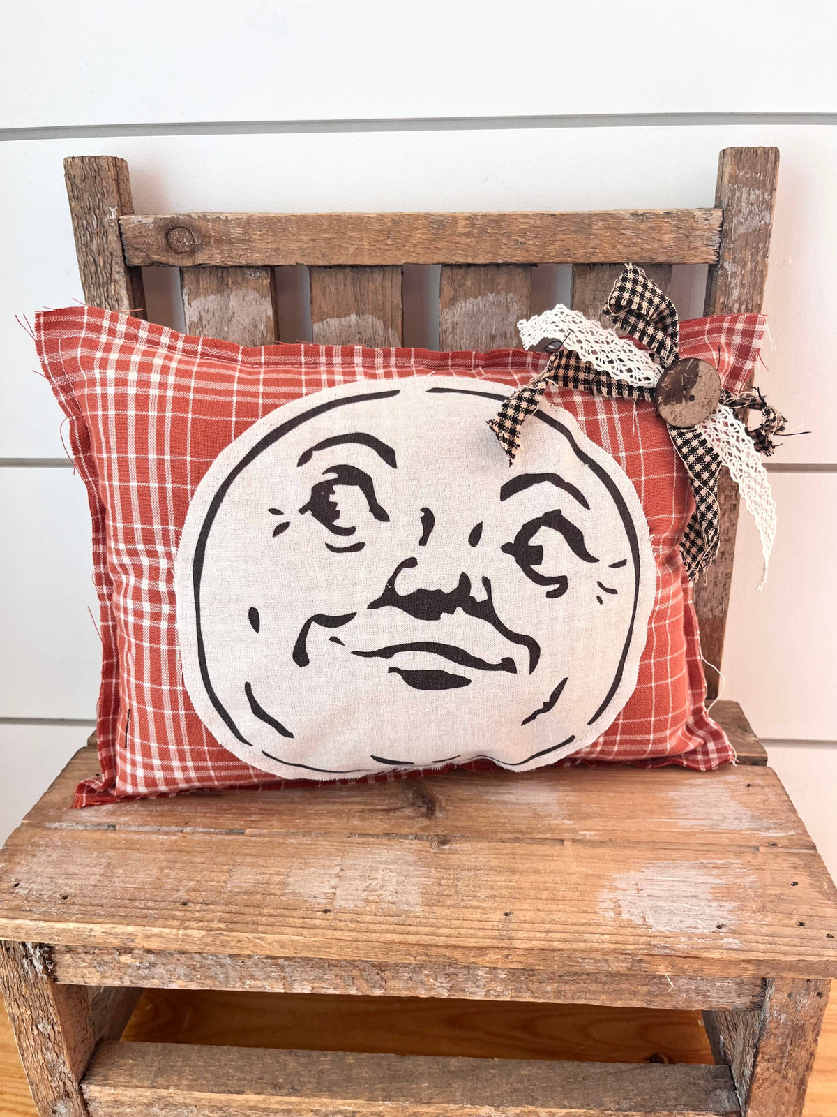 Red plaid decorative pillow featuring a vintage man-in-the-moon face.